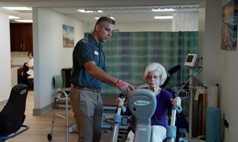 Physical therapist assisting an older adult with therapeutic exercise during a clinical therapy session