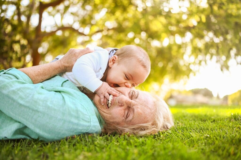 A mother and baby have a smile while being outdoors in the grass