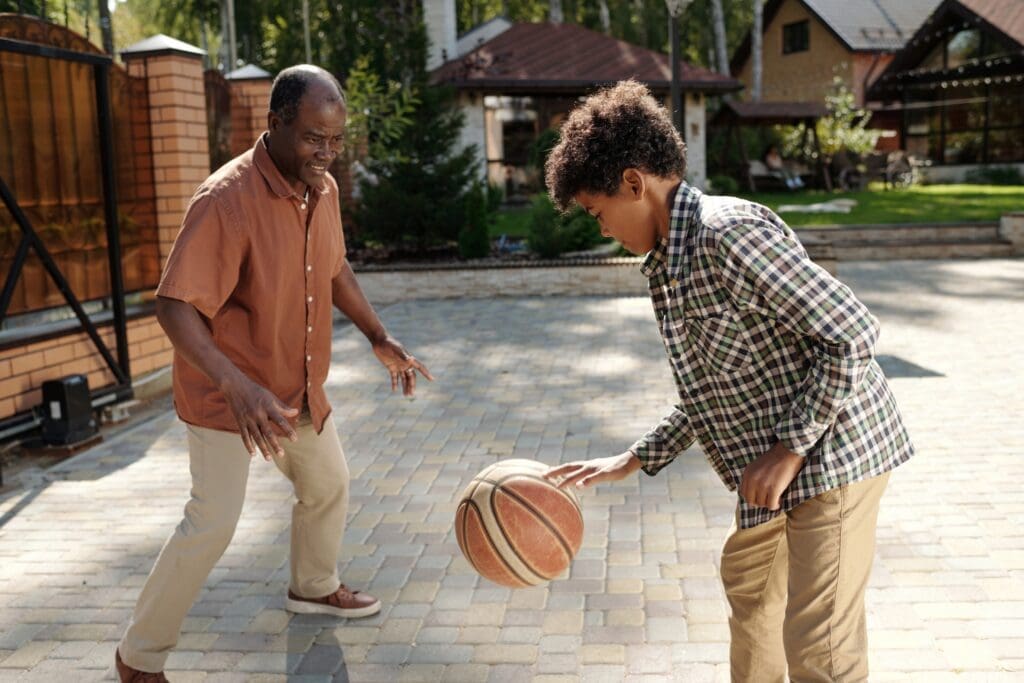 Two people playing basketball outdoors.